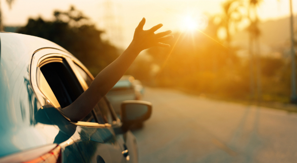 hand out the window of a car driving down the road