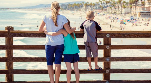 a woman and two young children looking out from the pier