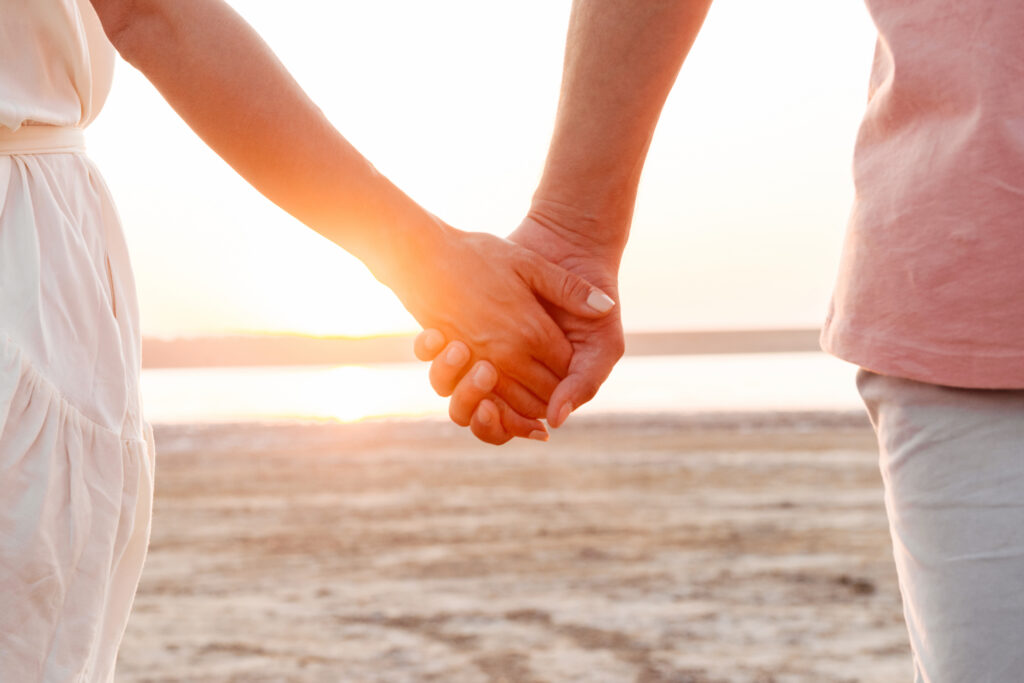 man and woman holding hands on the beach